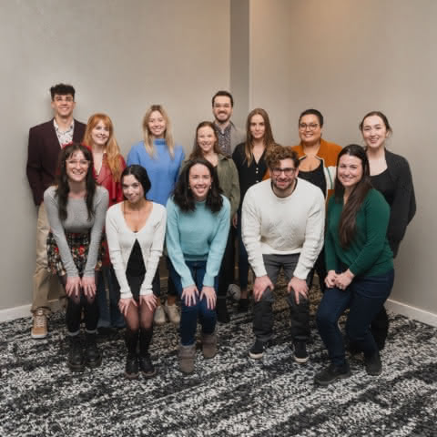 The Liden Digital Marketing team grouped in front of a neutral colored wall. There are 10 women and 3 men on the team.